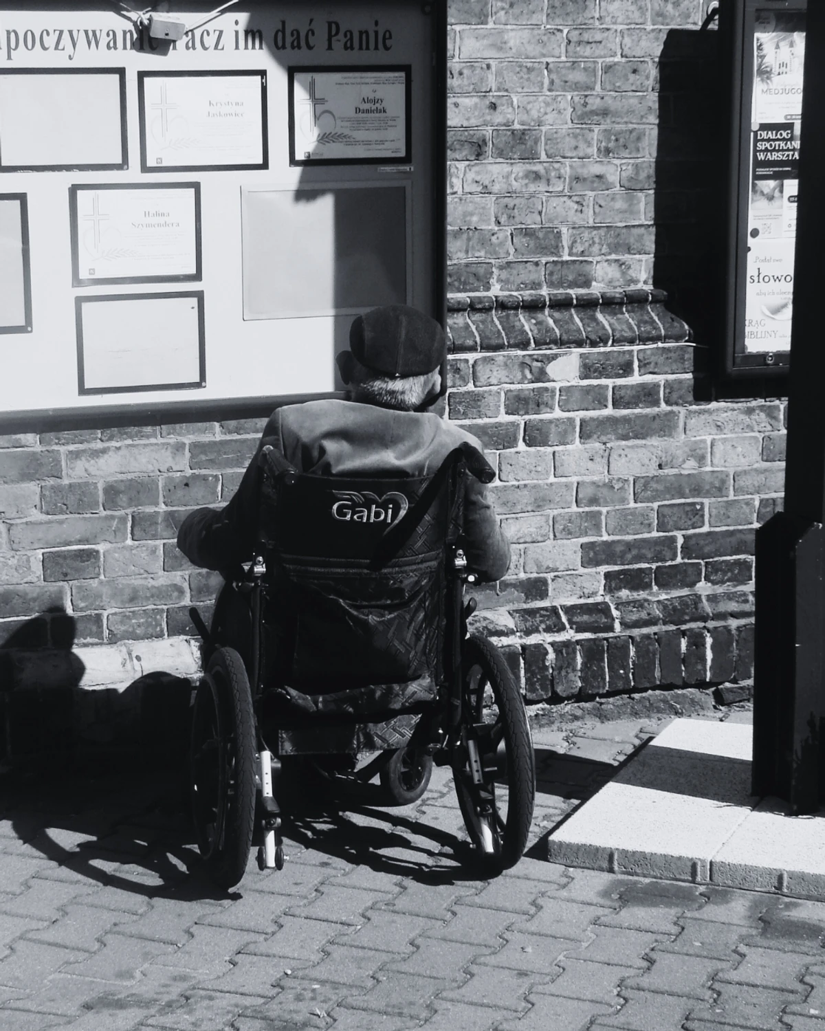 czlowiek na wózku i tablica ze zmarlymi